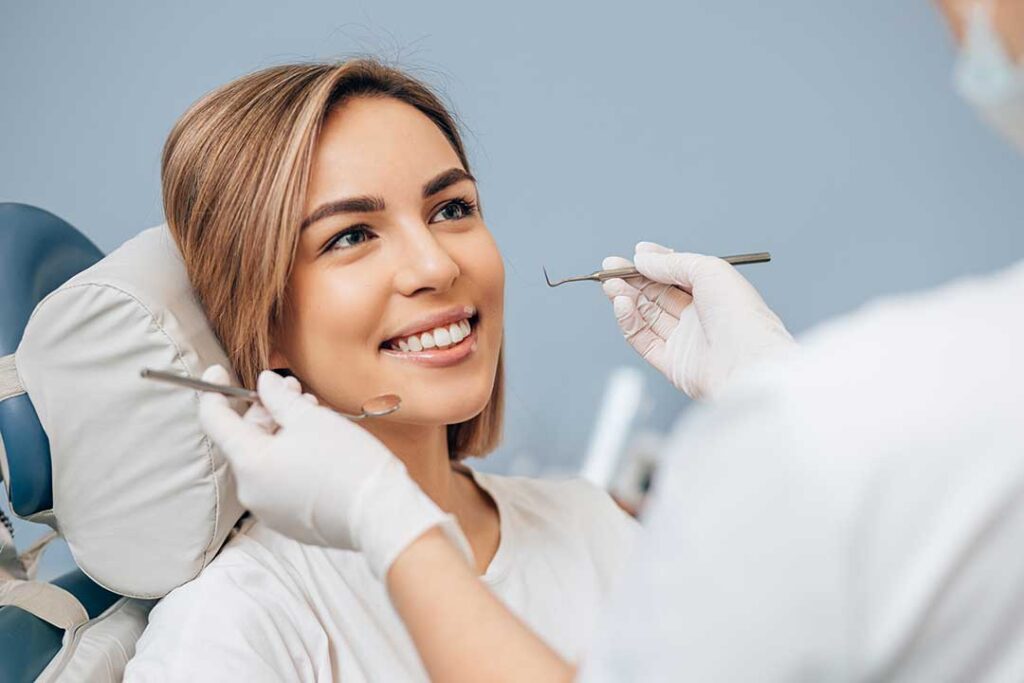 Person rinsing a chipped tooth while holding a small tooth fragment over a bathroom sink.