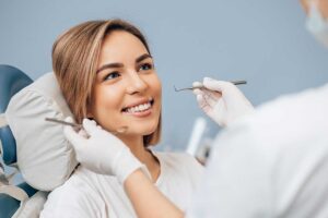 Person rinsing a chipped tooth while holding a small tooth fragment over a bathroom sink.